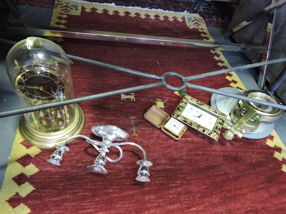 A skeleton mantel timepiece, a travelling timepiece, three other timepiecse and a candlestick.