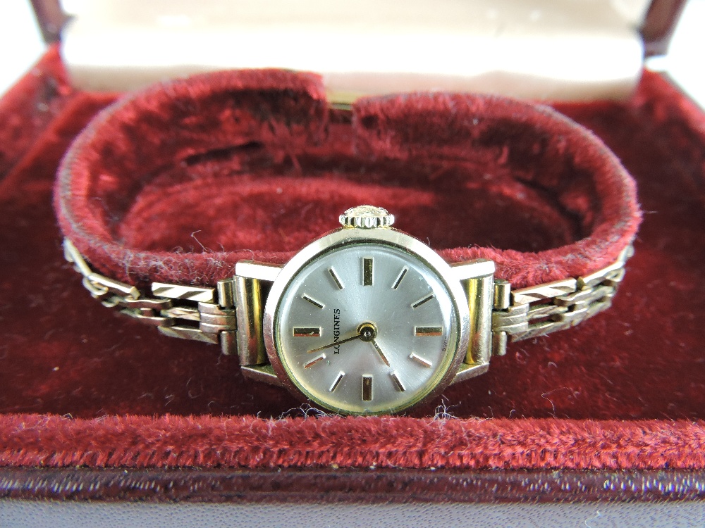 A Longines 9ct ladies wristwatch, the champagne dial set out with baton numerals, on an associated