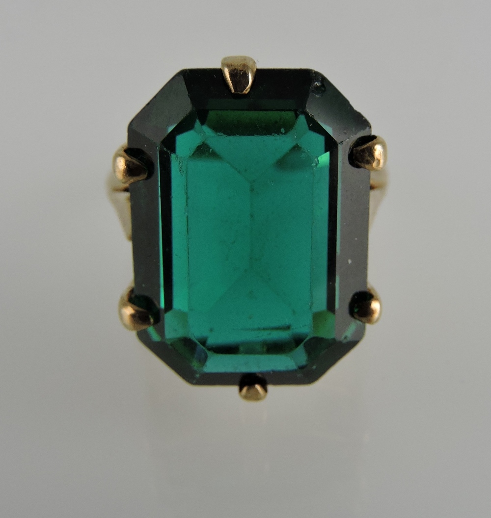 A green stone trap-cut dress ring, claw set in a yellow metal band stamped 9ct, 5.6g