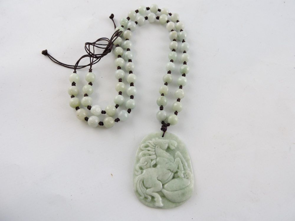 A Chinese jade bead necklace and pendant carved with a rearing stallion.