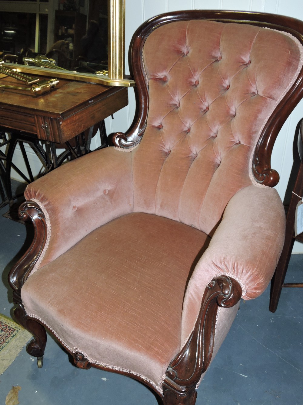 A Victorian mahogany spoonback armchair upholstered in buttoned pink draylon on carved cabriole