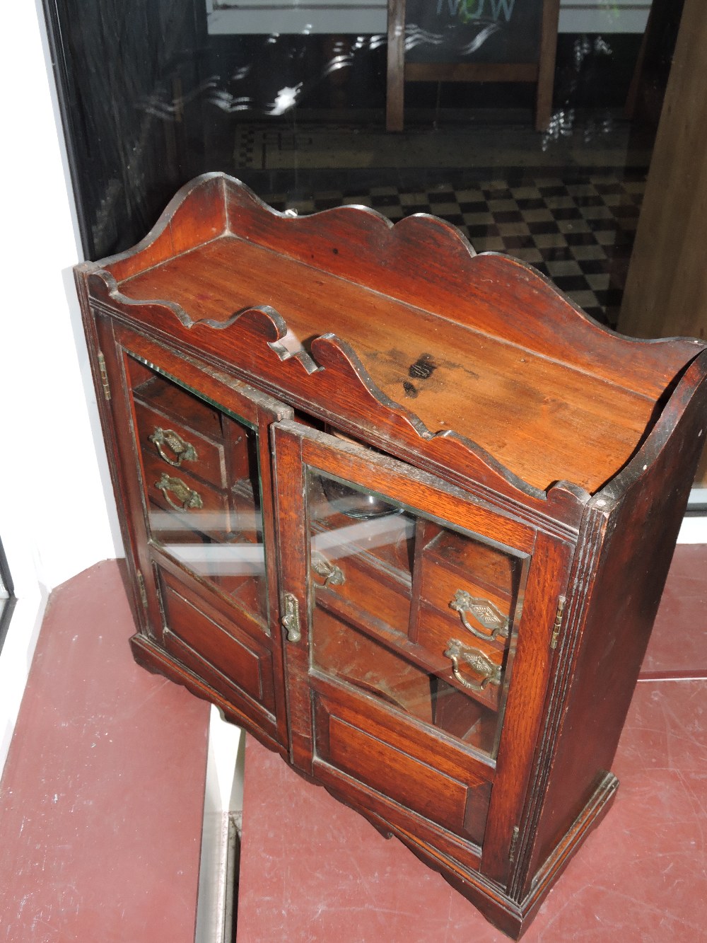 A late Victorian oak table top smoker's cabinet with shaped raised back over two glazed, panelled