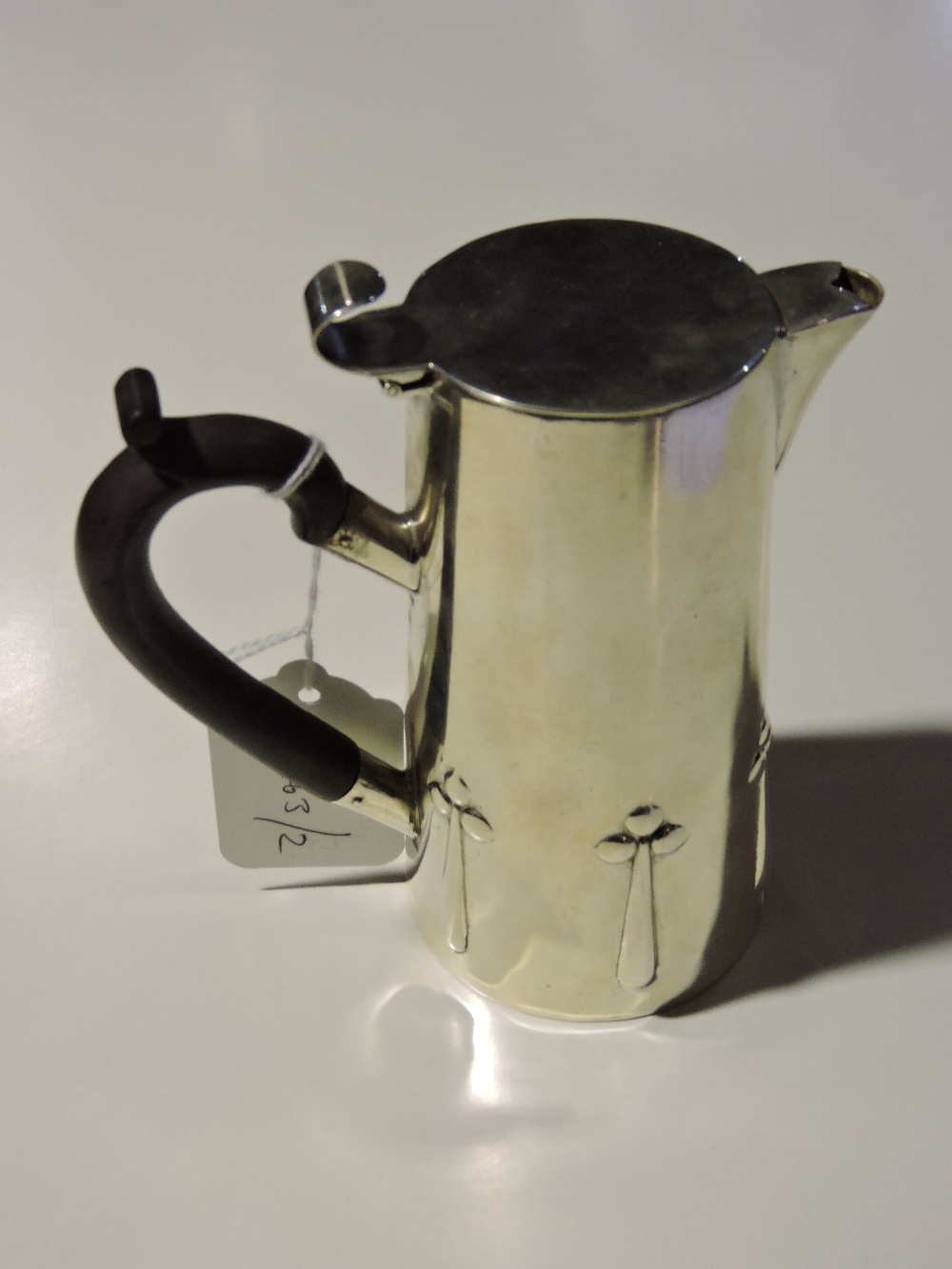 An Art Nouveau silver plated hot water jug with embossed stylised floral motifs. H. 14cm.