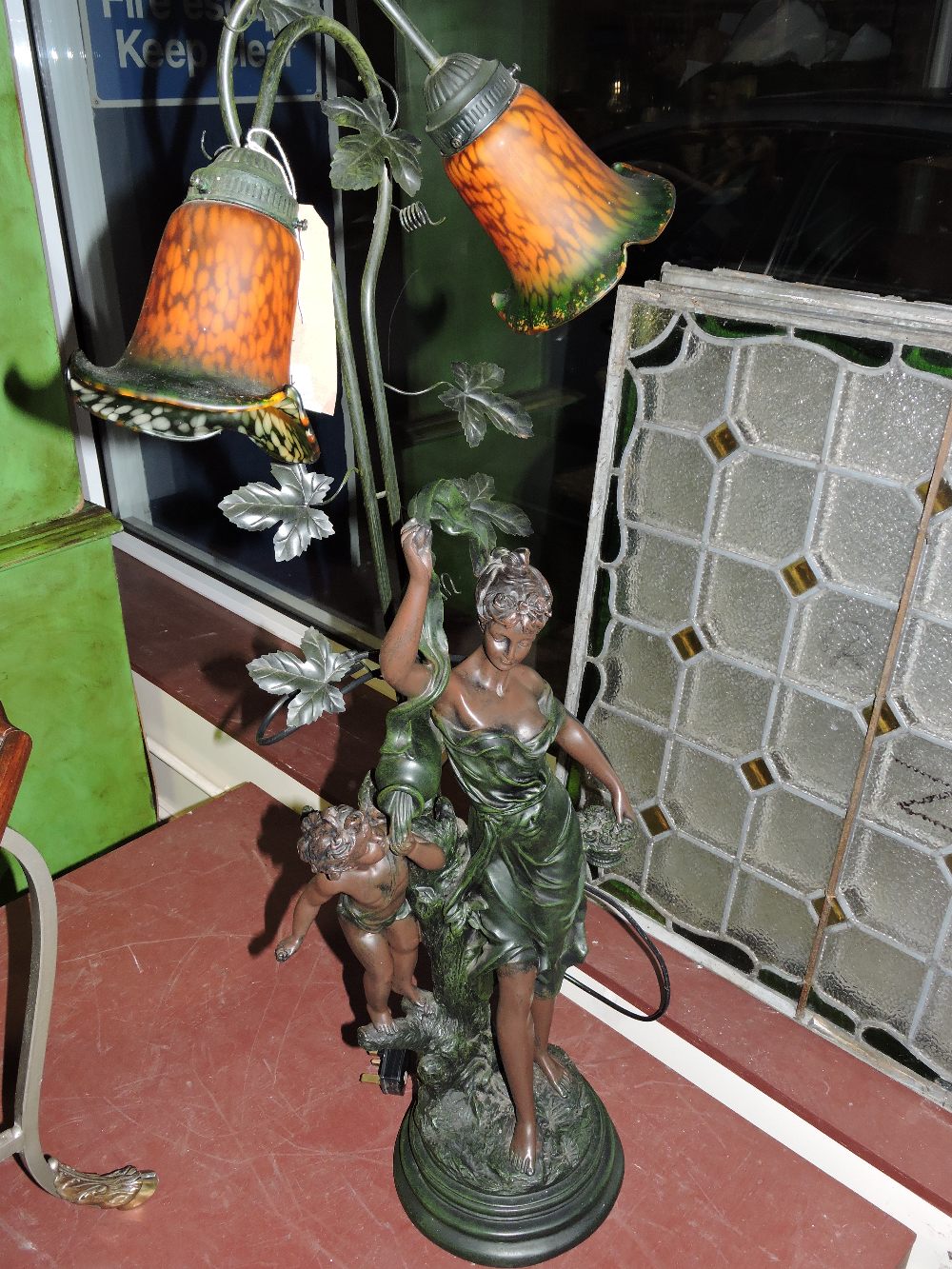 An Art Nouveau style bronzed figural two branch tablelamp modelled as a young maiden with cherub