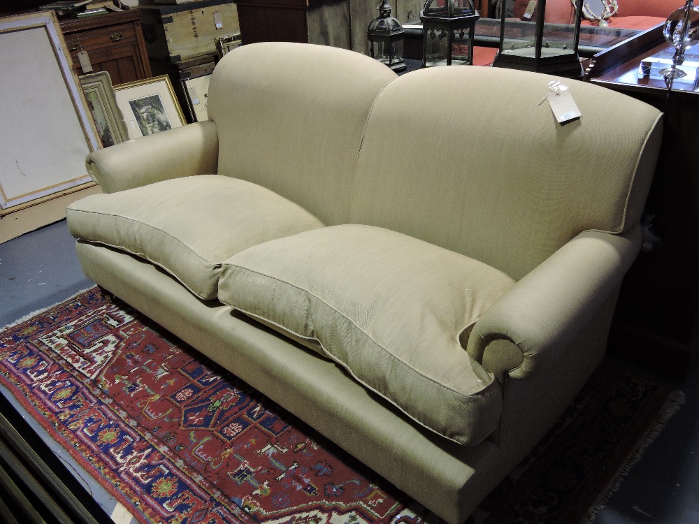 A Howard style three-seater settee, upholstered in pale gold fabric.