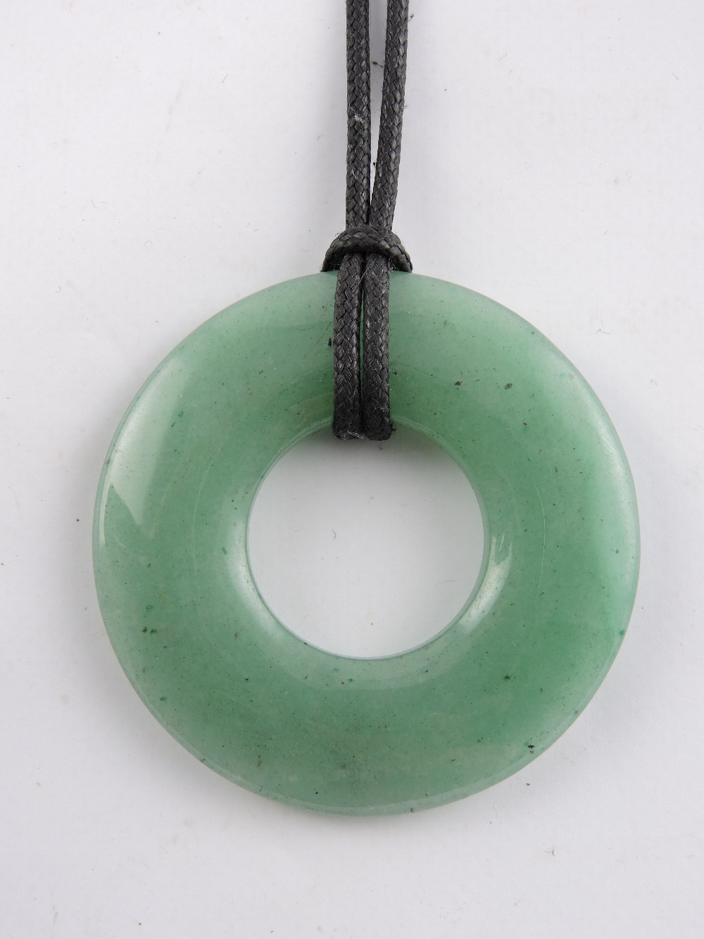A Chinese jade disc pendant on leather strap, Dia. 7cm.