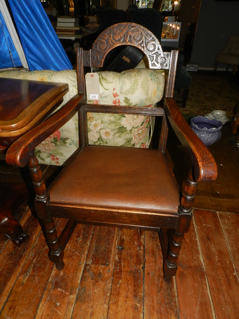 A 20th century oak elbow chair having arched carved cresting rail, moulded spar, drop in seat raised