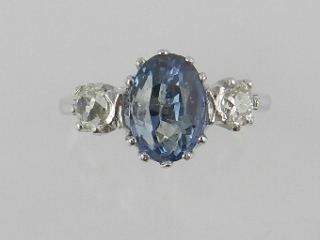 An 18ct white gold sapphire and diamond dress ring centred within a pale oval cut sapphire flanked