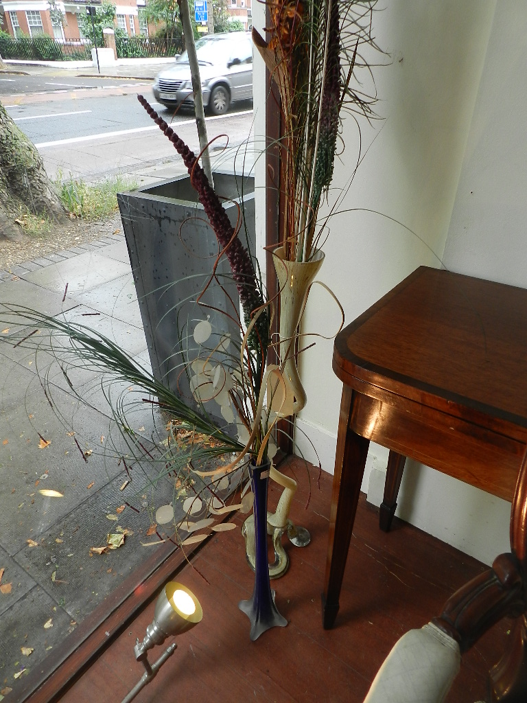 Three studio glass vases containing dry flowers and peacock feathers, together with a studio