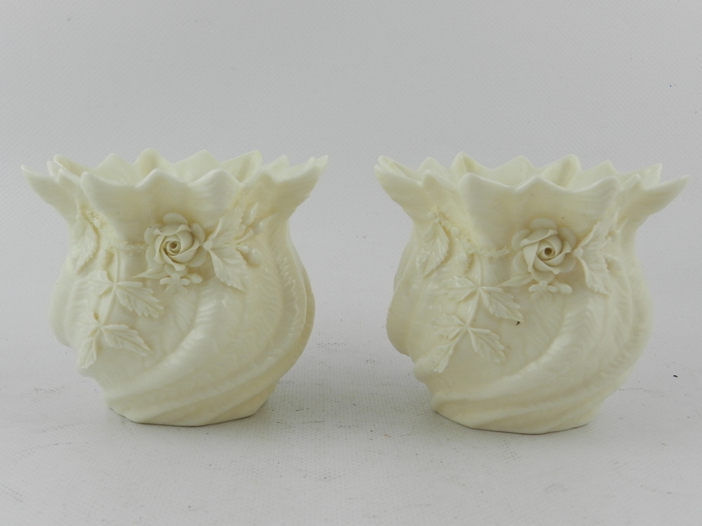 A pair of Irish Belleek hard paste porcelain squat vases of rythen form, decorated with flowers.