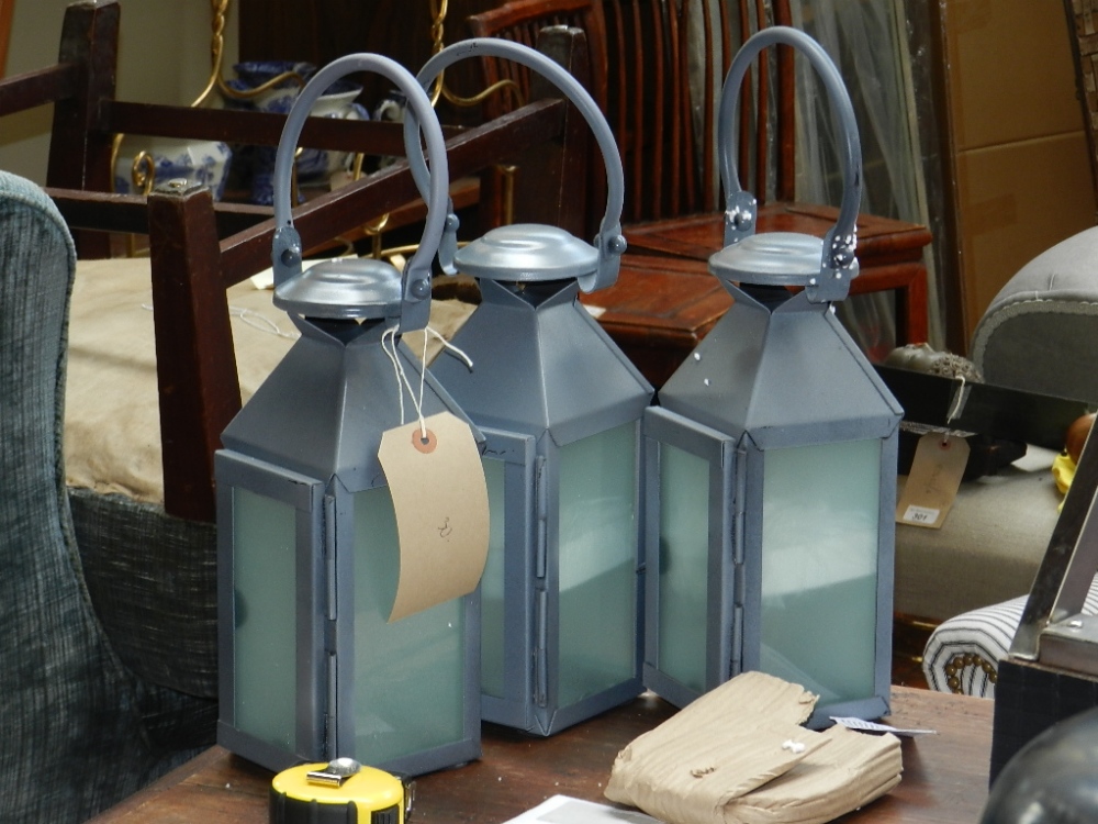 A set of three painted tin hanging lanterns, inset frosted glass plates.