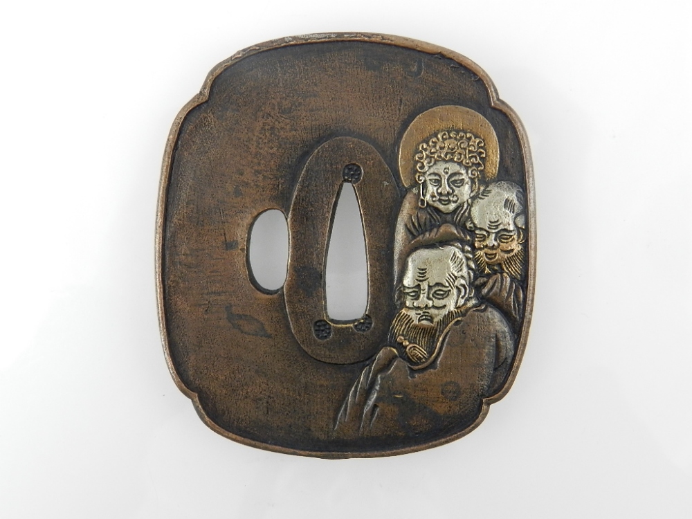 A Japanese cast bronze Katana tsuba, decorated to one side with stylised figures and opposing side