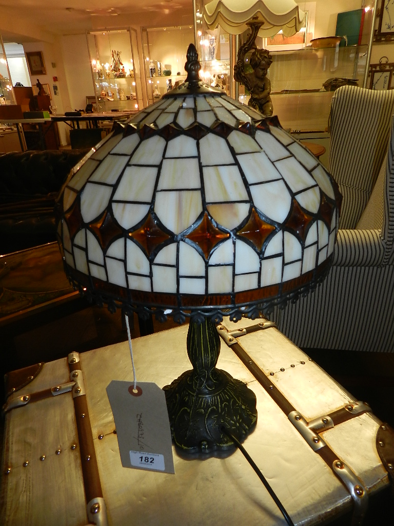 A contemporary Tiffany style table lamp, the leaded shade of cream and amber glass, raised on a cast