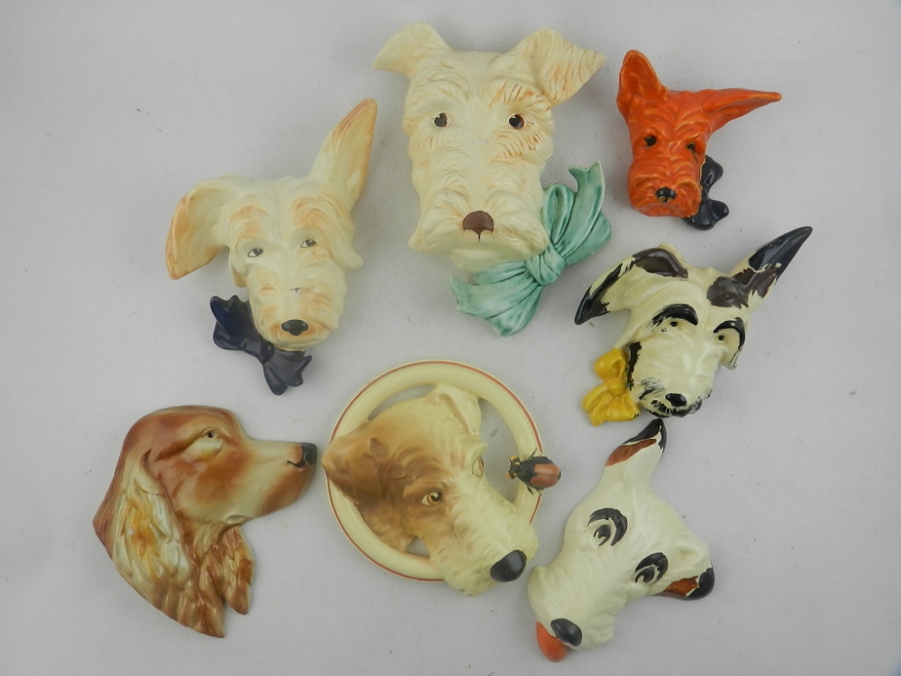 A collection of seven early 20th century pottery and ceramic wall plaques fashioned as dogs.