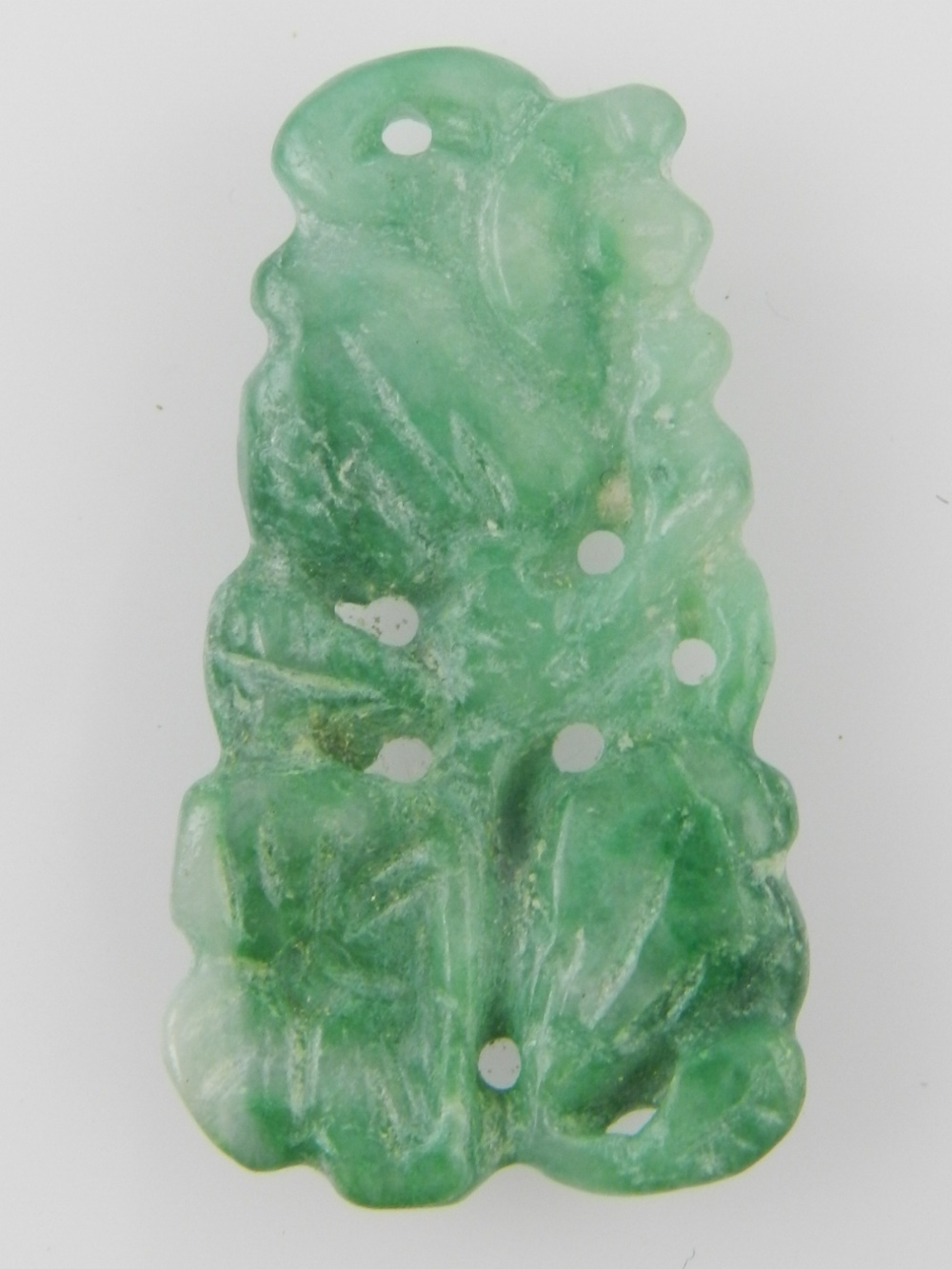 A green jade pendant of reticulated floral design.
