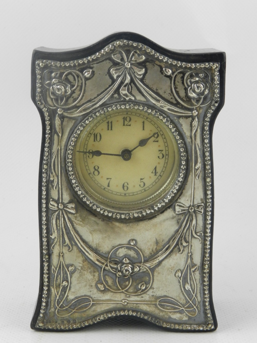 An Edwardian silver mounted and ebonised dressing table timepiece, embossed and decorated with