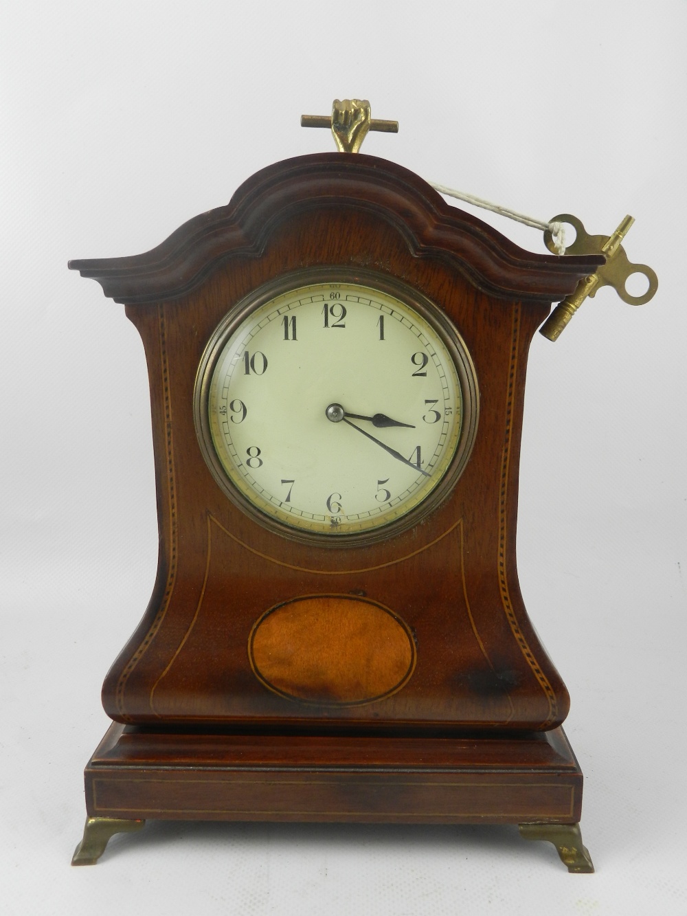 An Edwardian mahogany mantel timepiece, in the Dutch taste, boxwood and ebony checker line inlaid,