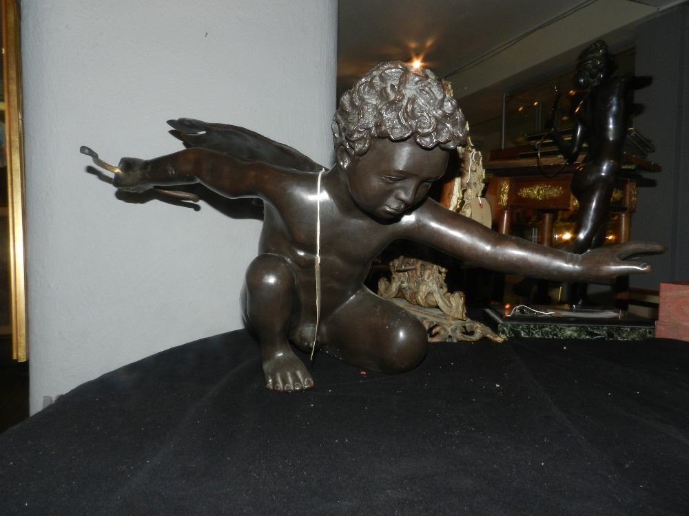 A bronze study of kneeling Cupid, outstretched arms. H.38cm L.76cm