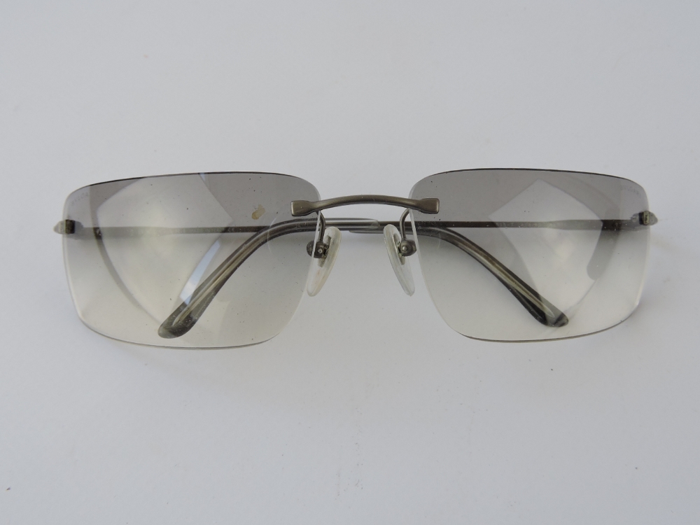 A pair of Bulgari frameless sunglasses, graduated grey lenses within a branded black leather case.