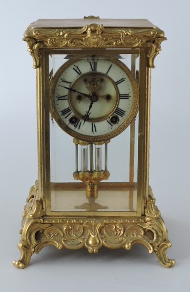 An early 20th Century Ansonia gilt brass four glass mantel clock, the circular white dial with