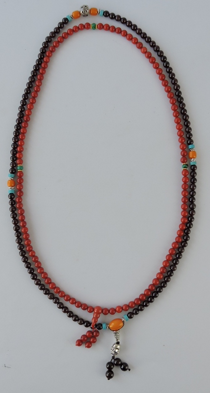 A coral necklace of uniform beads, interspersed with three jade beads and a drop, L. 68cm;