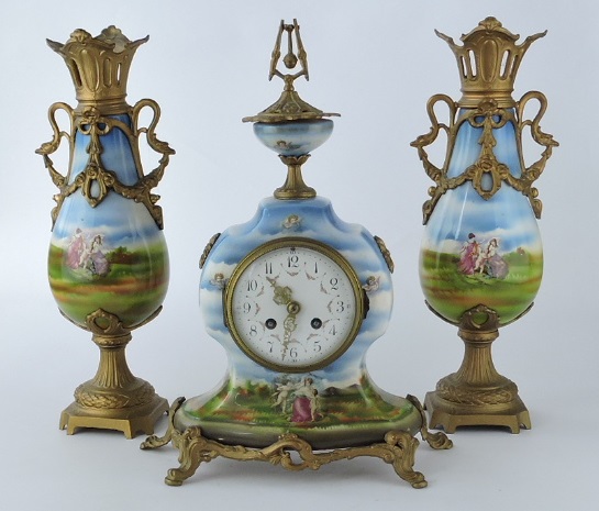 An early 20th Century continental porcelain and gilt spelter three piece clock garniture decorated