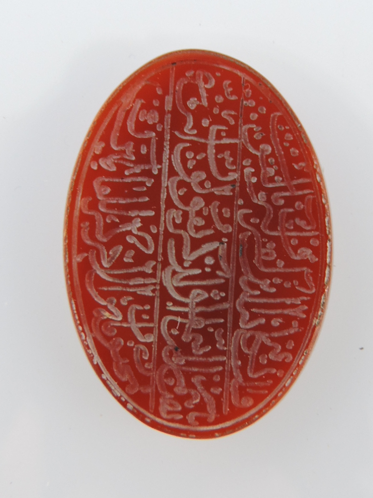 A red agate oval disc, engraved with Islamic script.