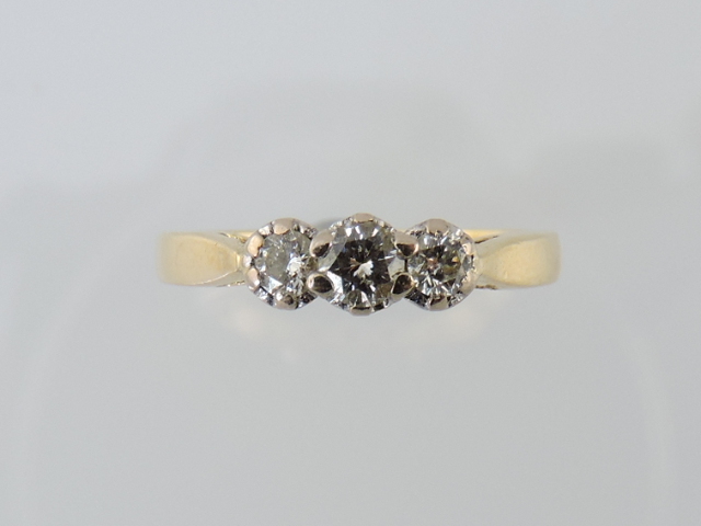 A three-stone diamond ring, in an 18ct gold band, 2.6g.