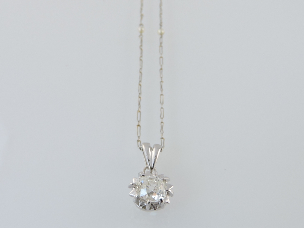 A solitaire diamond pendant, with an open claw setting, on a fine chain set with freshwater pearls.