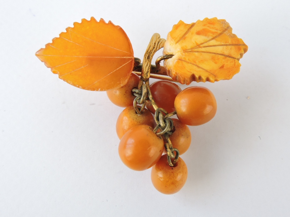 An amber brooch, modelled in the form of a bunch of grapes, with two leaves, gilt metal spine and