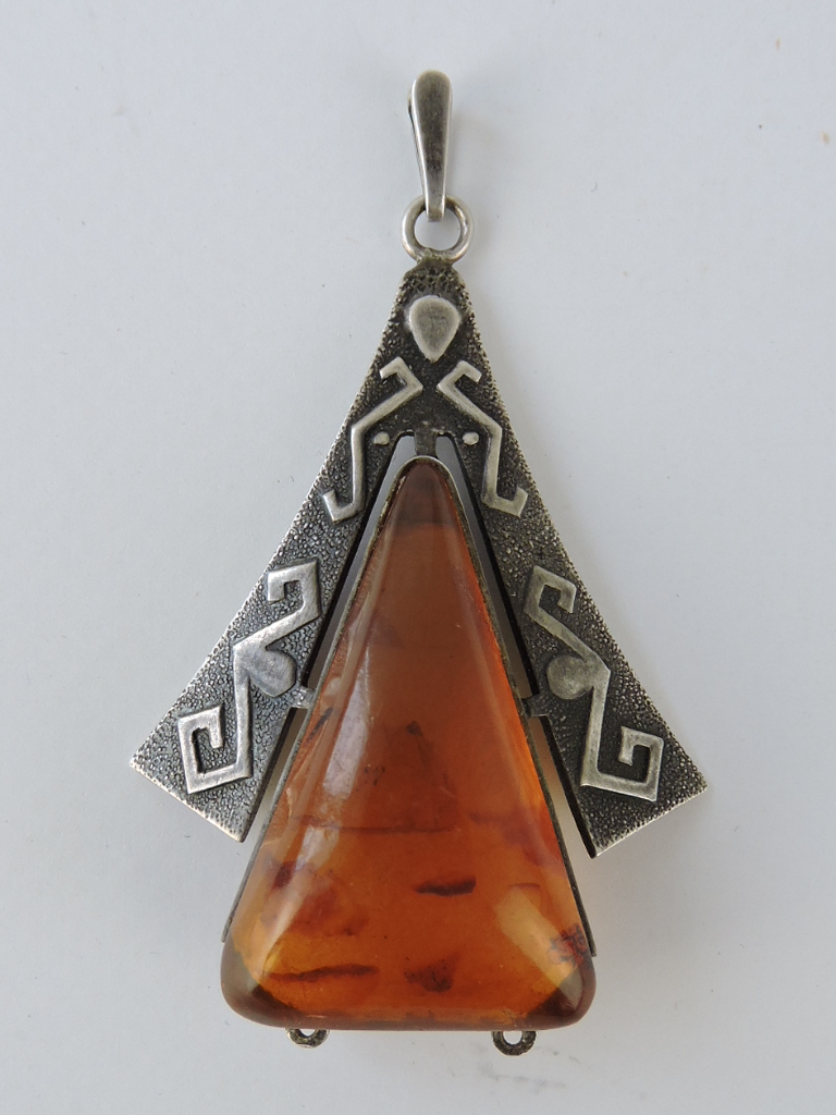 A Russian Art Deco style triangular amber drop, in a white metal frame, L. 6.5cm.