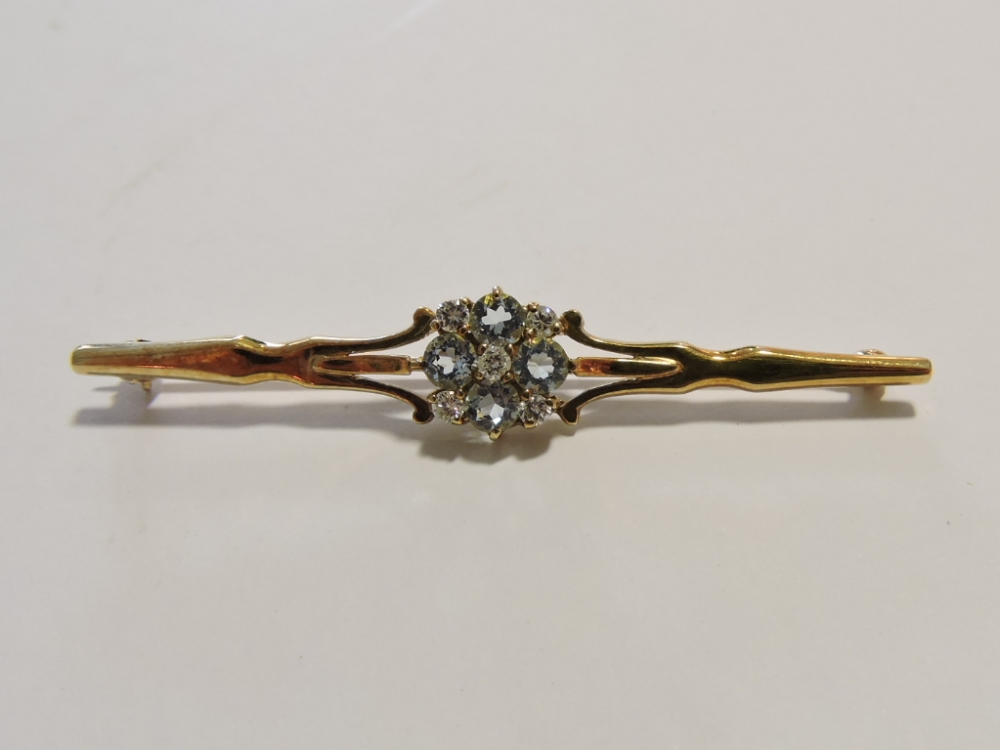 An Edwardian aquamarine and diamond bar brooch, the nine stones in a cluster flowerhead on a 9ct