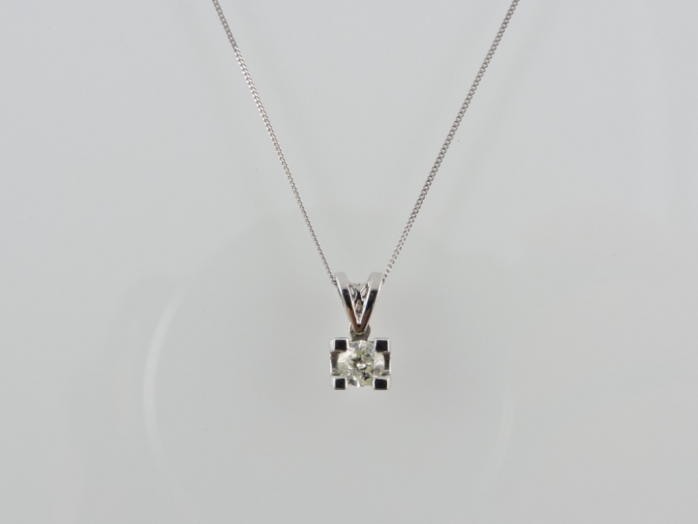 A diamond solitaire pendant, claw set in 18ct white gold, in a 9ct white gold fine link chain, 0.