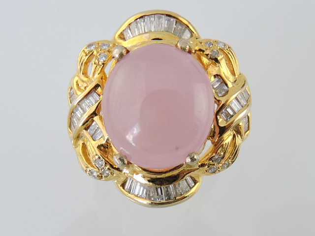 A cabouchon-cut pink sapphire and diamond ring, claw set within scrolls of pavé set diamonds in an