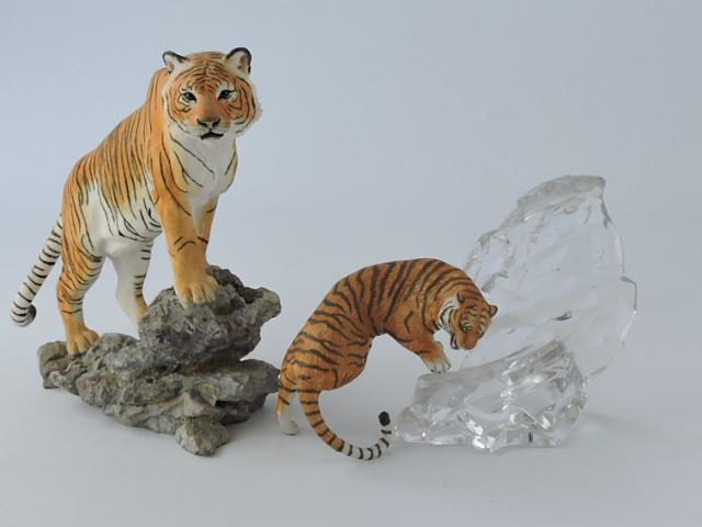 A resin cast model of a tiger on a rocky outcrop, H. 47cm; together with another on a glass mount.