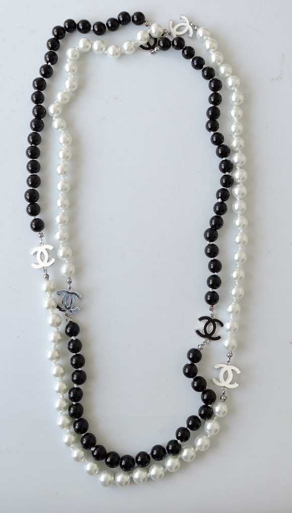 A Chanel-style white and black bead necklace, the sections divided by entwined C-motifs, L. 150cm.