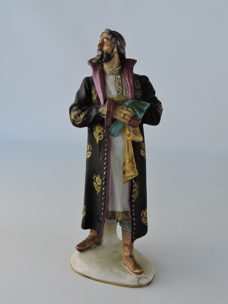 A porcelain figure of Boris Godunov, standing in black gilt-decorated coat with puce lining, H.