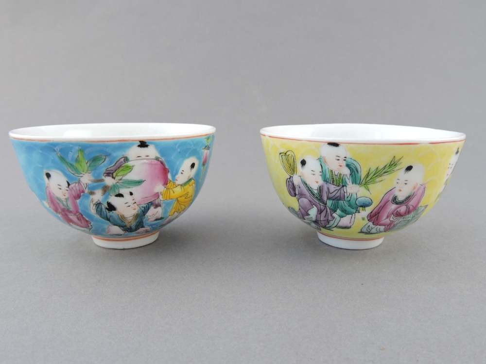 A pair of tea bowls, depicting frolicking figures, one on a turquoise ground, the other yellow, D.