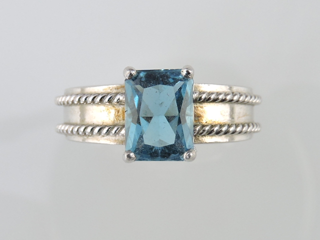 A blue stone dress ring, possibly tourmaline, the rectangular cut stone in claw setting on a