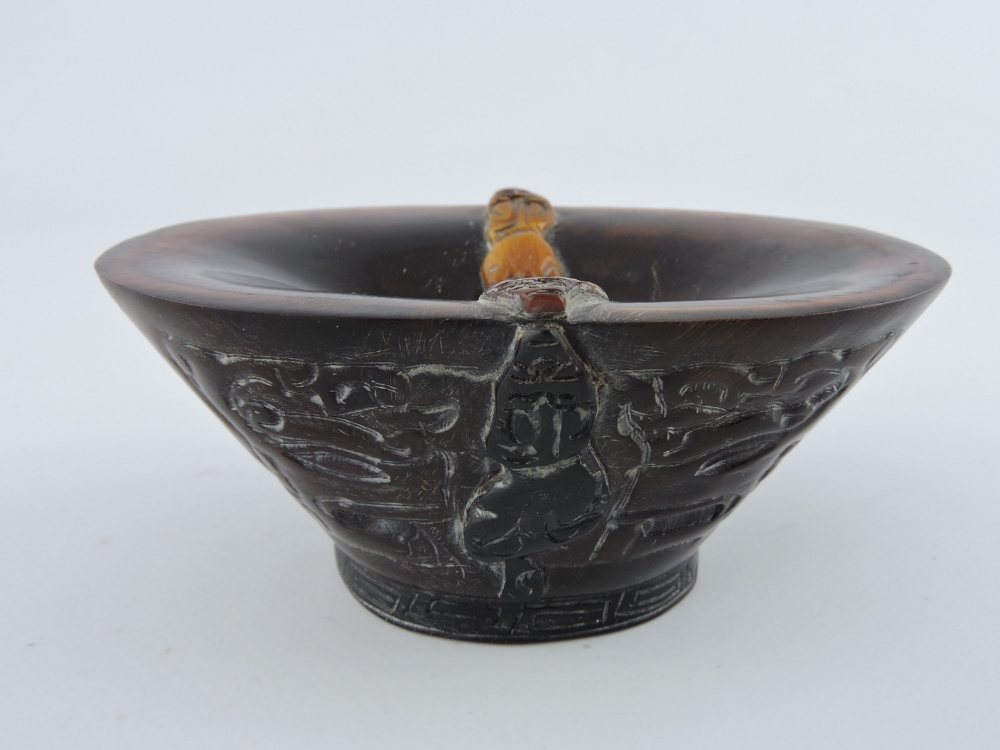 A Chinese libation cup, of boat shape, carved with traditional motifs, W. 12cm.