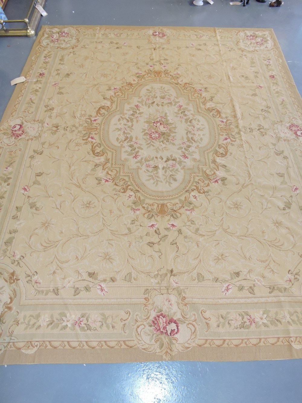 An Aubusson style gold ground needlepoint carpet woven with central cartouche rose panel within