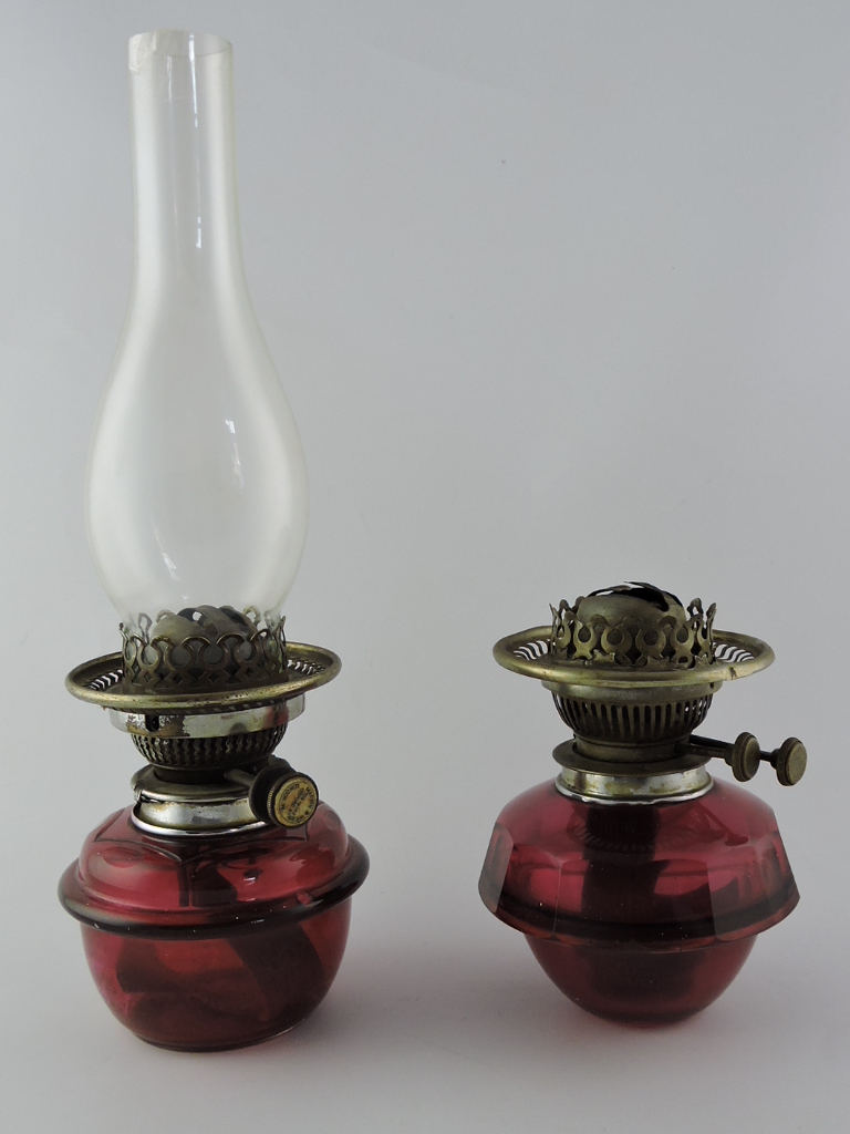 Pair of Victorian cranberry glass oil lamp resevoirs with one clear glass chimney, one bears