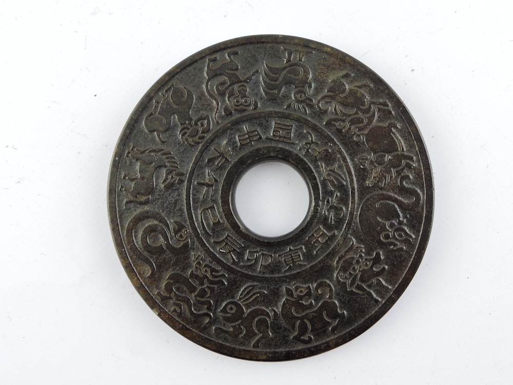 A Chinese hardstone pi-disc, carved with zodiac symbols, D. 12cm.