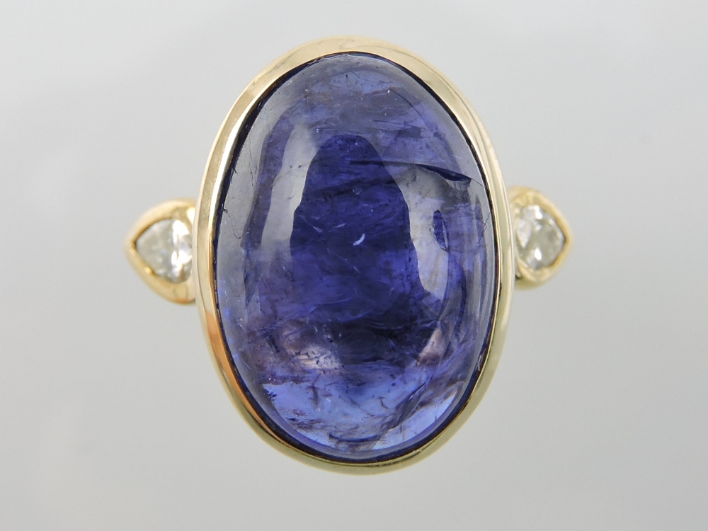 A blue gemstone ring, oval cabouchon cut of approx. 10cts, set in a yellow metal band with pear-