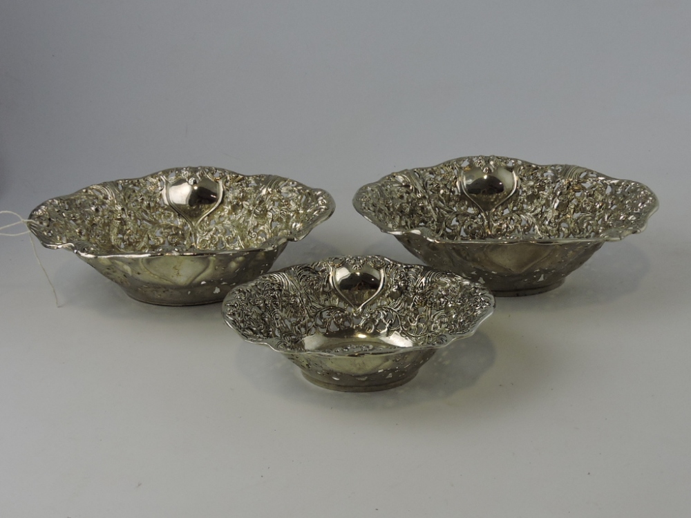 Three white metal pierced bowls, vacant cartouches, largest W. 21cm.