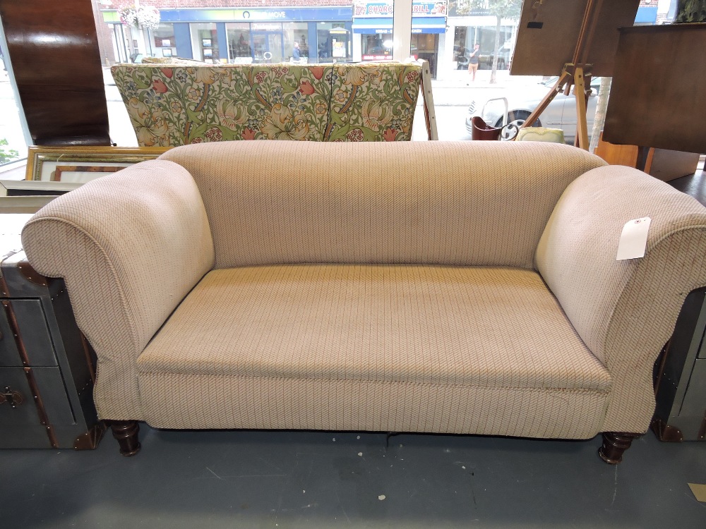 A late Victorian upholstered double drop-arm Chesterfield settee, on turned tapering feet.