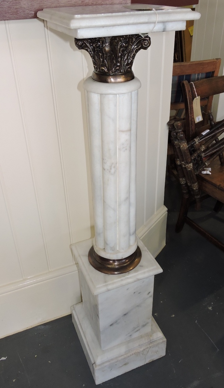 A pair of white marble stands, of reeded form with gilt metal Corinthian capitals, on square