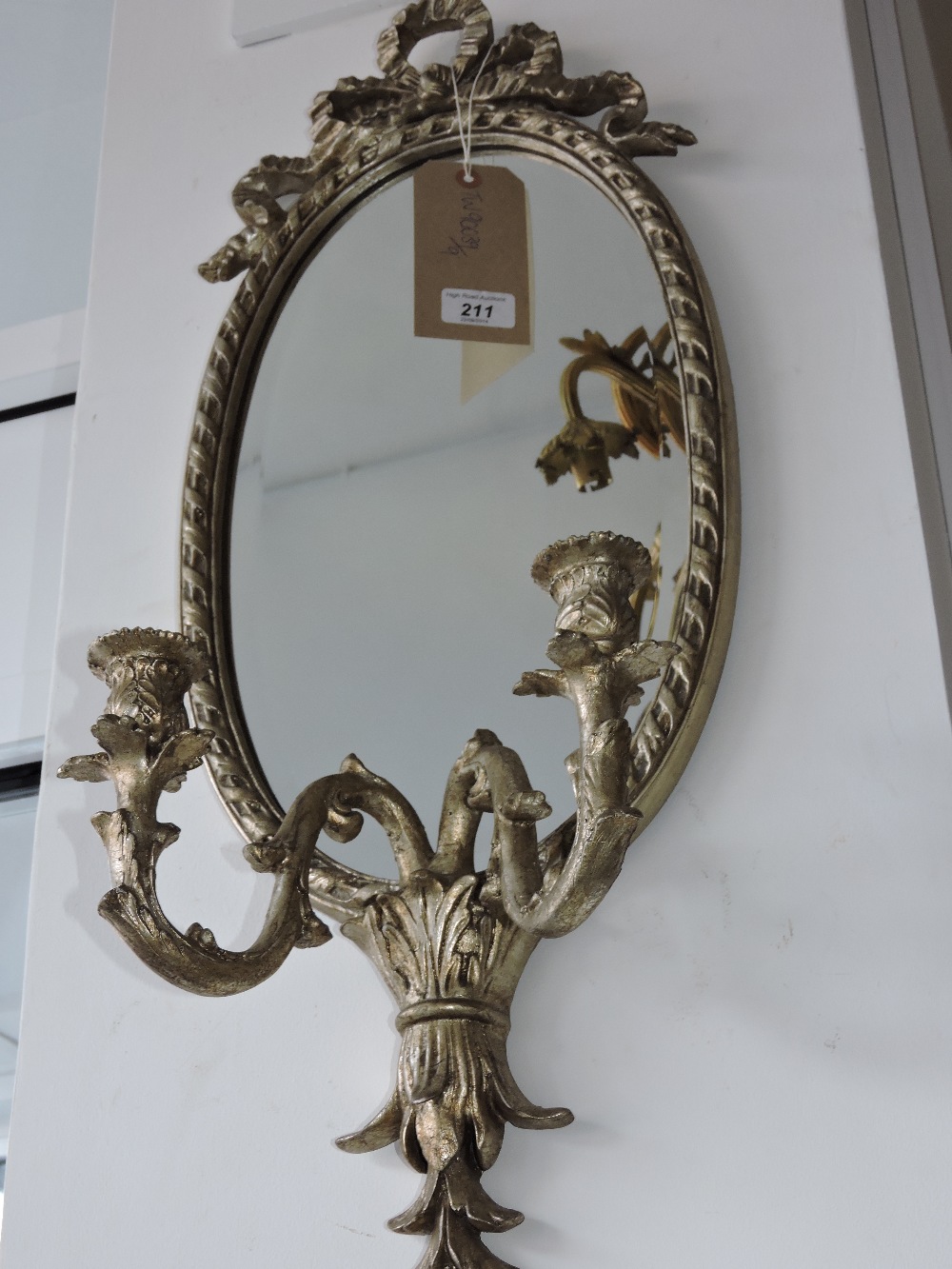 An oval girandole mirror, with a ribbon tie surmount and foliate swan-neck branches, H. 76cm.