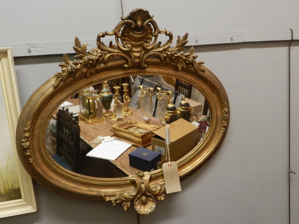 A 19th century gilt wooden gesso-framed oval looking glass, having shell and leaf carved crest,