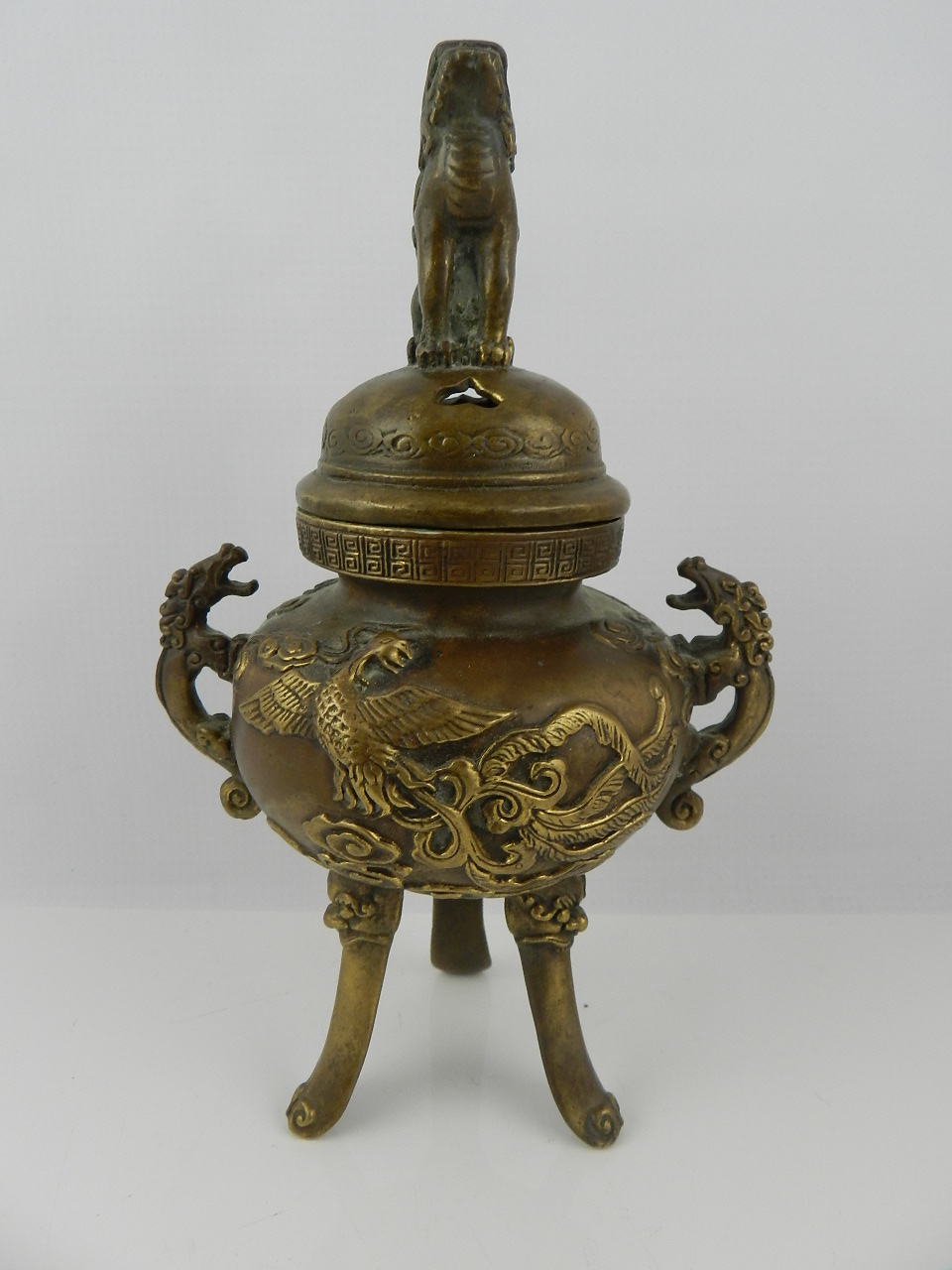 A Chinese bronze incense burner, pierced kylin mounted dome top lid, twin dragon handles, relief